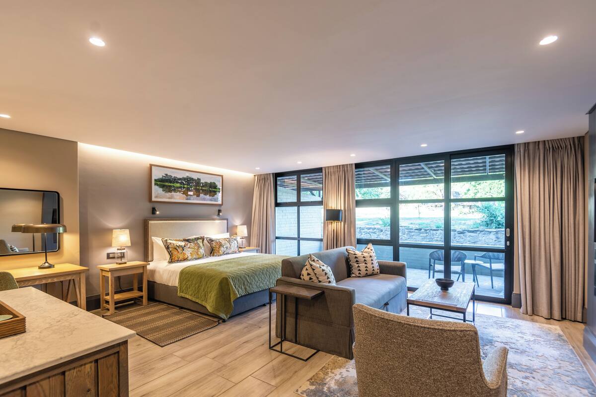 Una habitación de hotel moderna con cama, sofá, escritorio y zona de comedor.