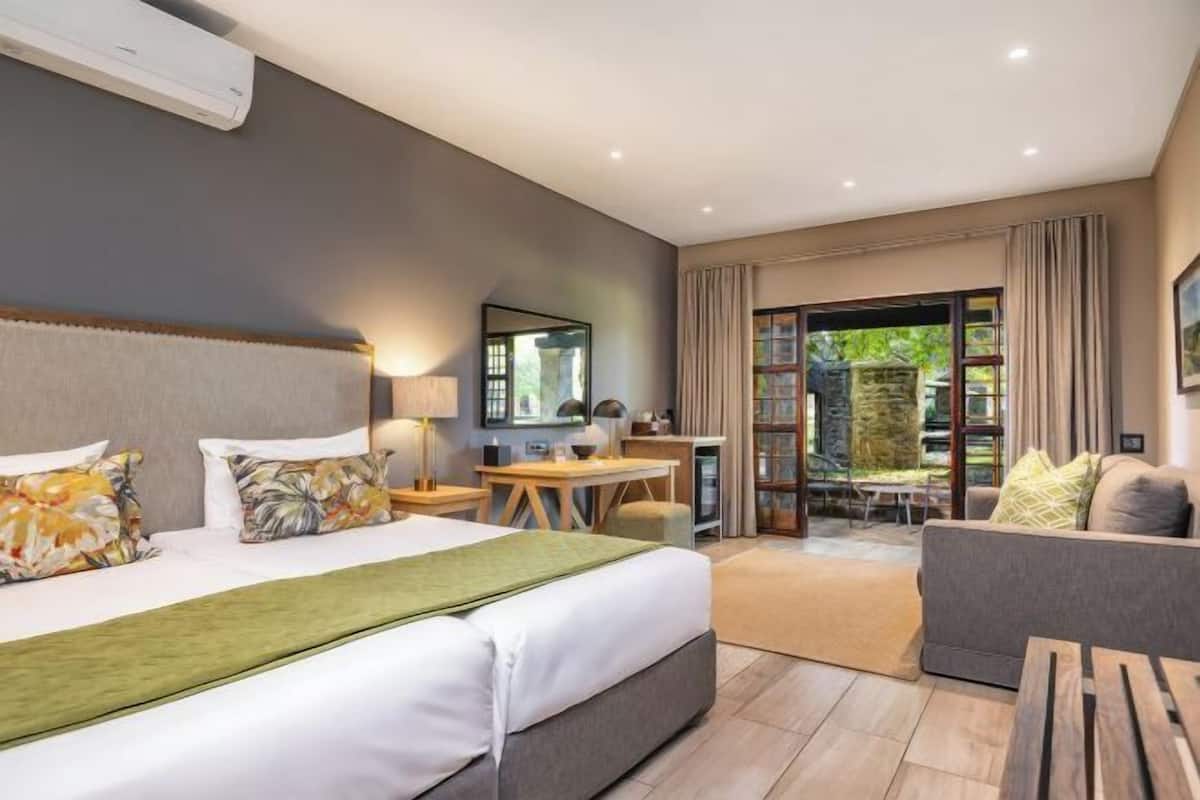 Habitación de hotel con cama, escritorio, sofá y vistas al exterior.