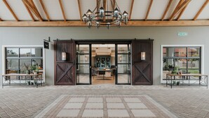 A spacious entrance with a chandelier, wooden beams, and a view into the interior. - Midgard (Okahandja)