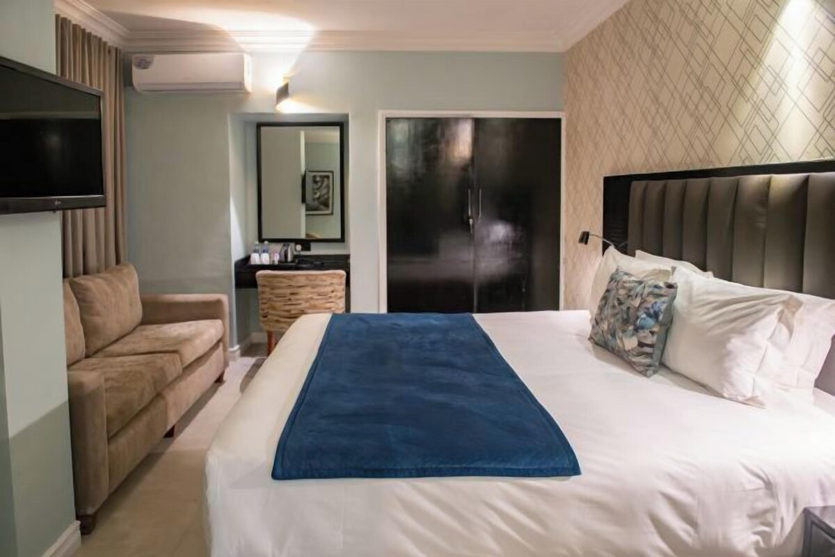 Una habitación de hotel con cama, televisión, zona de estar y baño.