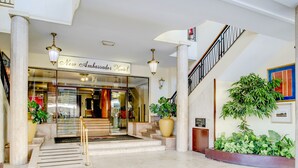 A hotel entrance with a glass door, a staircase, and potted plants. - New Ambassador Hotel (Harare)