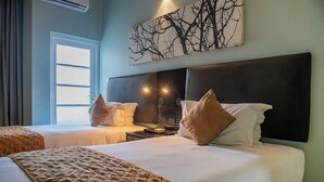A hotel room with two beds, a large window, and a wall-mounted artwork. - New Ambassador Hotel (Harare)
