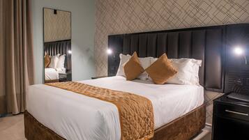 A neatly made bed with a quilted blanket, a headboard with a geometric pattern, and a mirror above it.