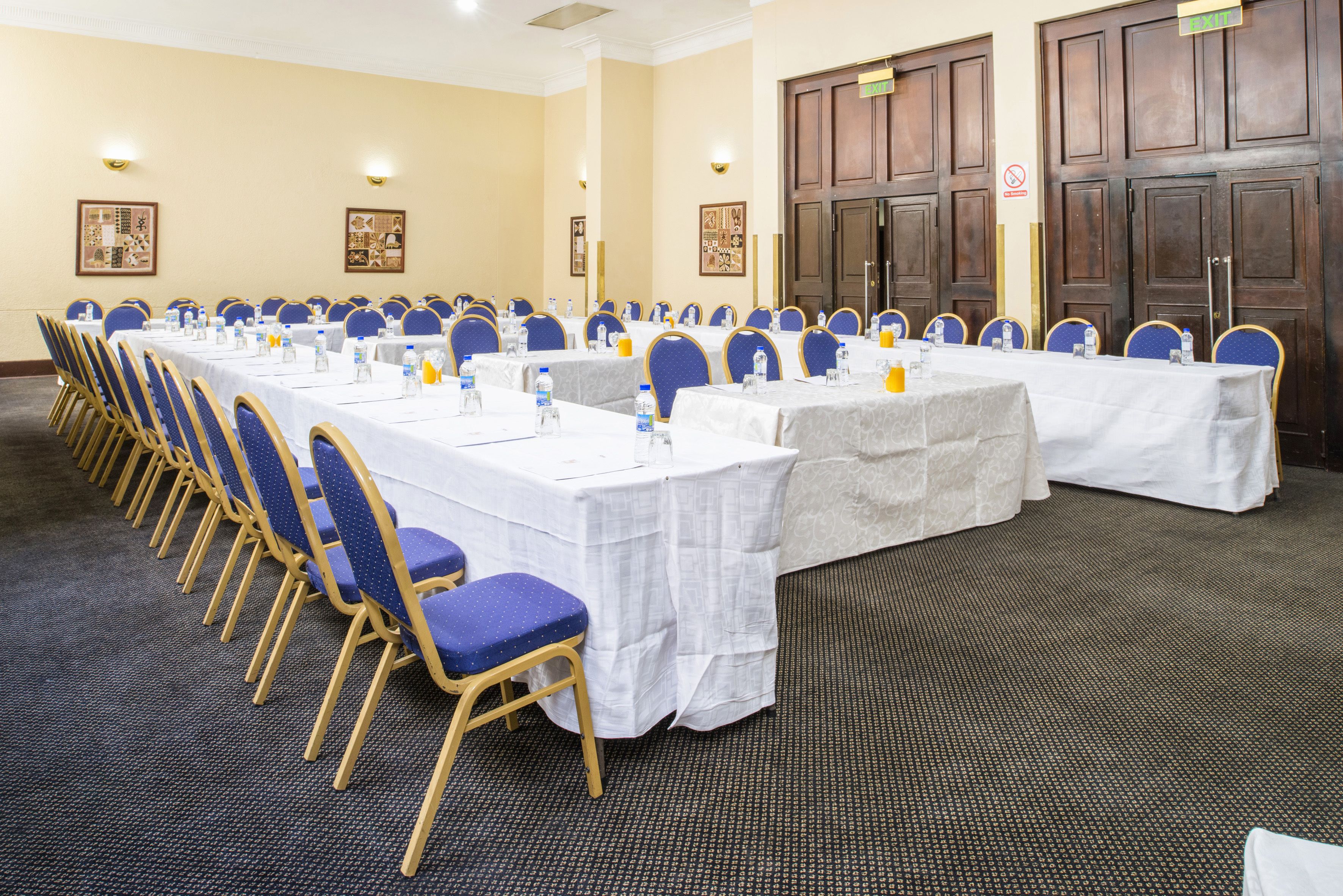 Un salón de conferencias con filas de mesas y sillas, equipado con botellas de agua y tarjetas de identificación.