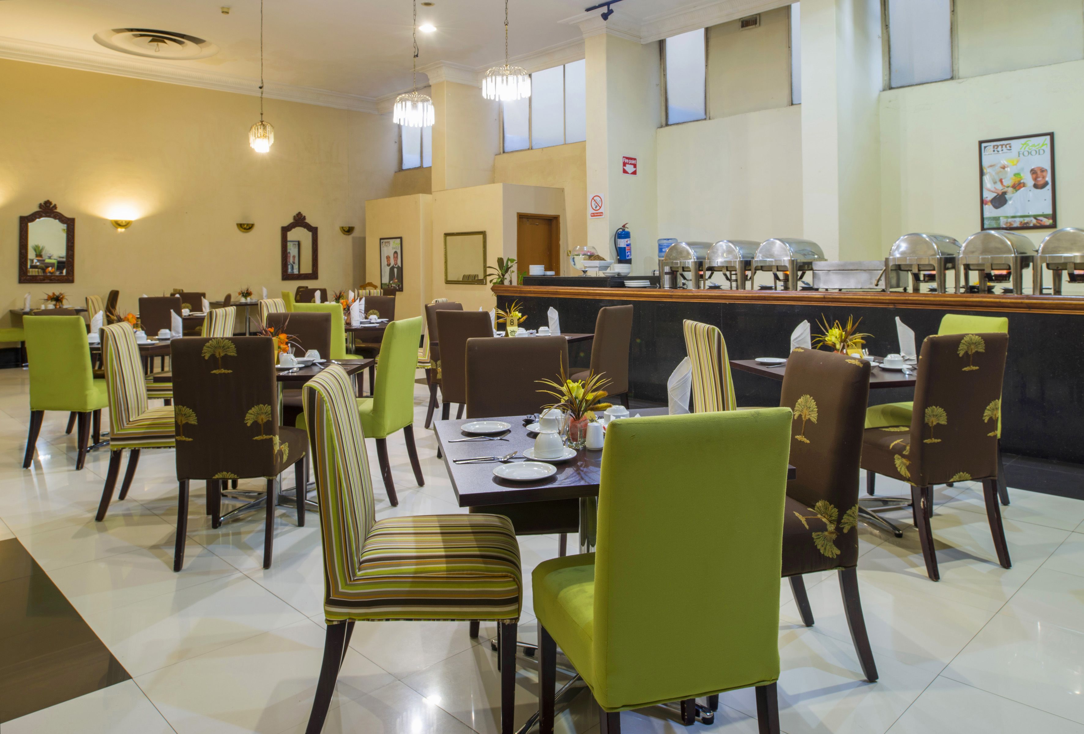 A restaurant with multiple dining tables and chairs, a buffet area, and a counter with food service equipment.