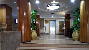 A lobby with a reception desk, a staircase, and potted plants. - New Ambassador Hotel (Harare)