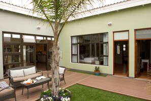 A modern hotel with a patio area featuring a sofa, a coffee table, and a potted plant. - Namib Guesthouse (Swakopmund)