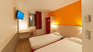Habitación de hotel con dos camas, un escritorio, una silla, un televisor y una cortina roja.