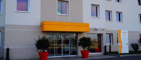 A modern building with a flat facade, large windows, and a prominent orange awning.