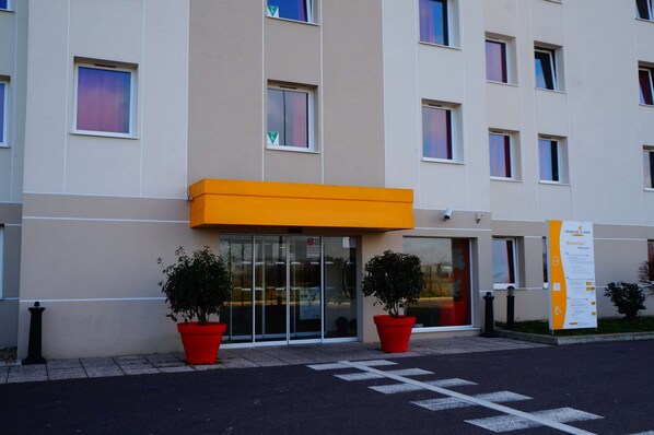 Un edificio moderno con fachada plana, ventanas amplias y un llamativo toldo naranja.