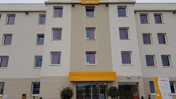 Un hotel con un letrero amarillo que dice 'Premiere Classe Hotels'. Tiene varios pisos con ventanas y una entrada central con puertas de cristal.