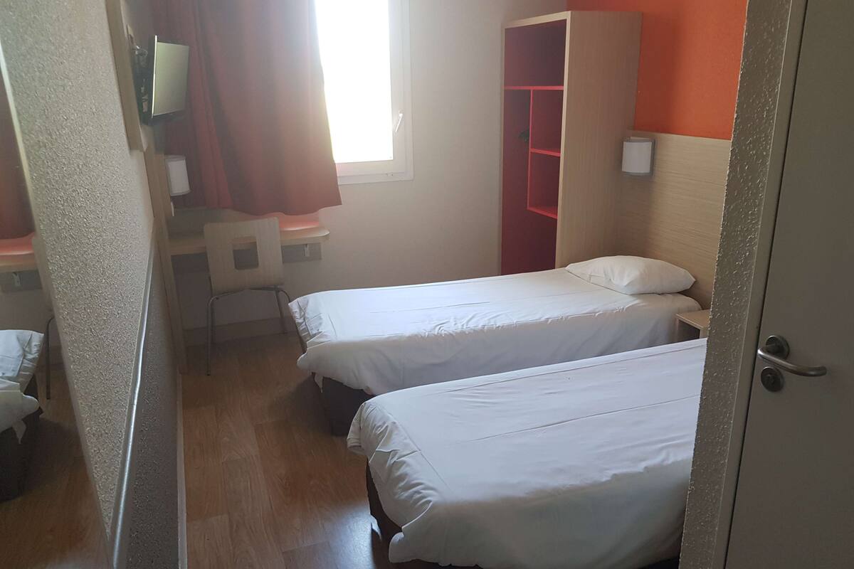 A room with two beds, a desk, a chair, and a wardrobe.
