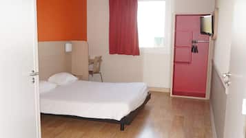 Un dormitorio con cama, ventana con cortina roja, suelo de madera y armario rojo.