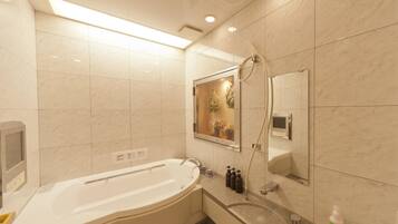 A modern bathroom with a freestanding bathtub, a handheld showerhead, a built-in toilet, and a vanity with a mirror.