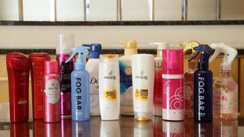 Diversos produtos de higiene pessoal dispostos sobre uma superfície espelhada.