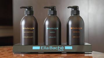 Tres botellas de acondicionador, champú y gel de ducha Ella Baché Paris sobre una encimera de mármol.