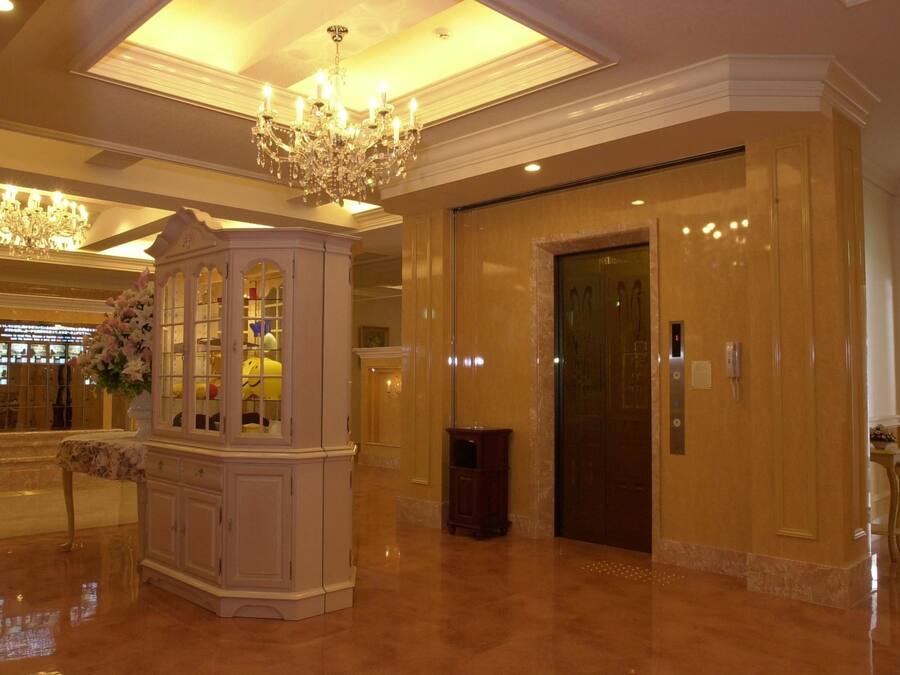 A lobby with a chandelier, a cabinet with glass doors, and an elevator.