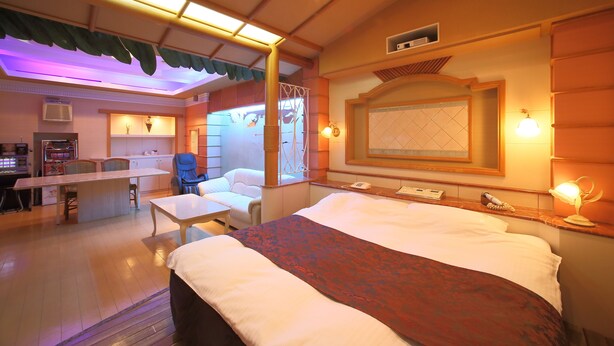Una habitación de hotel con cama, escritorio, silla y una pequeña zona de estar.