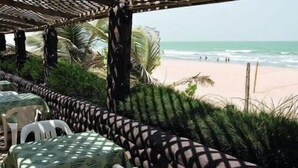 A beachside patio with outdoor seating and a view of the ocean. - Holiday Beach Club Hotel (Serrekunda)