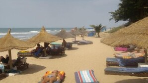 A beach with thatched umbrellas and sun loungers. - Holiday Beach Club Hotel (Serrekunda)