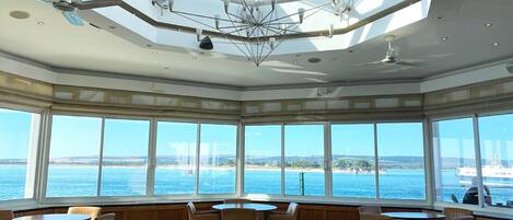 A sunlit room with large windows, a geometric ceiling design, and multiple seating areas.