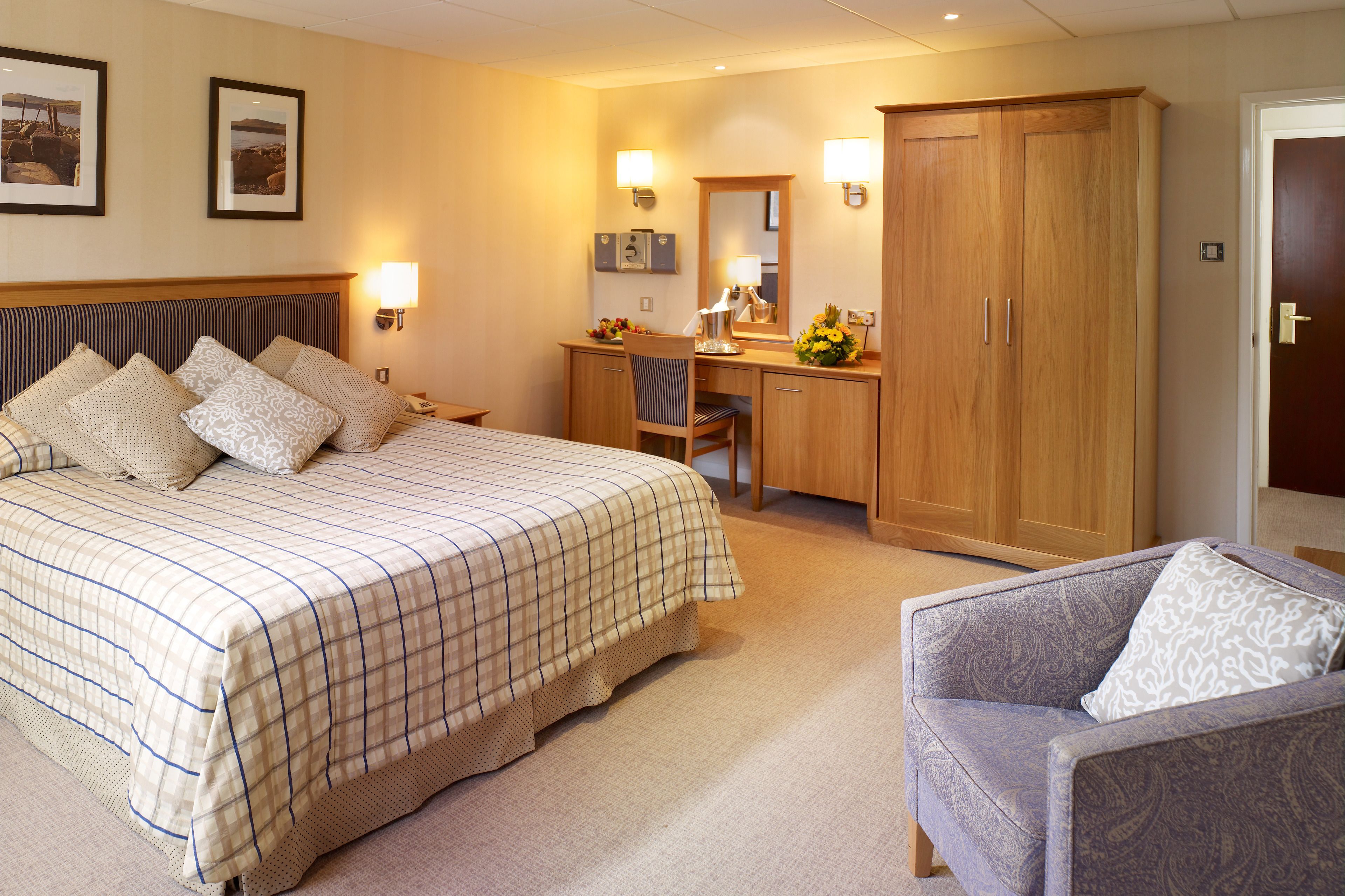 A hotel room with a bed, a desk, a chair, and a wardrobe.