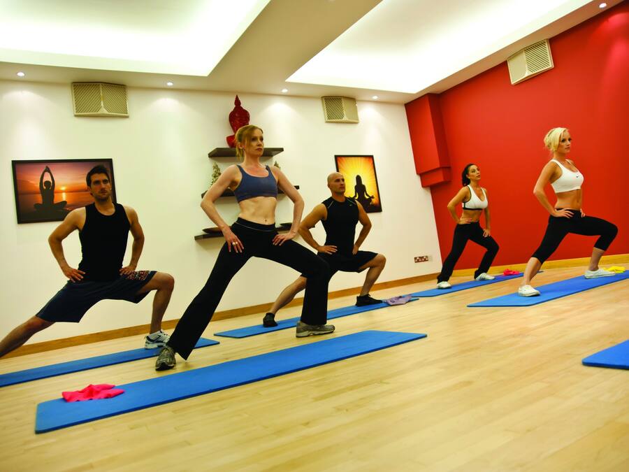 A group of people in a gym with blue mats on the floor, wooden walls, and red accents.