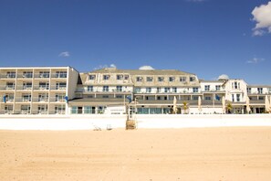 A beachfront hotel with multiple balconies, a sandy beach in the foreground, and a clear blue sky. - Sandbanks Hotel (Poole)