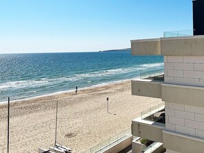 A beach with a clear view of the ocean and a building with a balcony overlooking the beach. - Sandbanks Hotel (Poole)