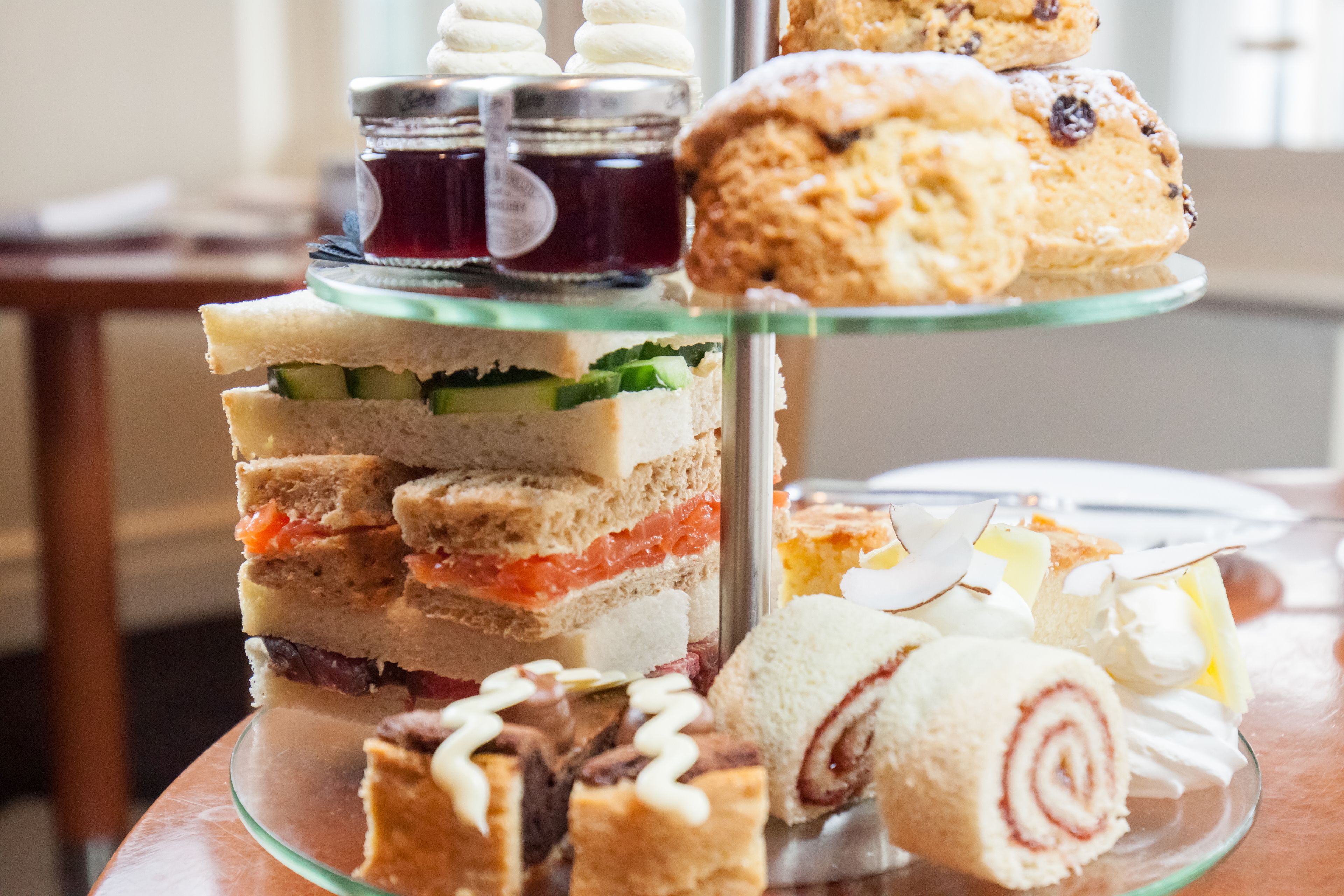 A multi-tiered dessert display with various pastries and sandwiches.