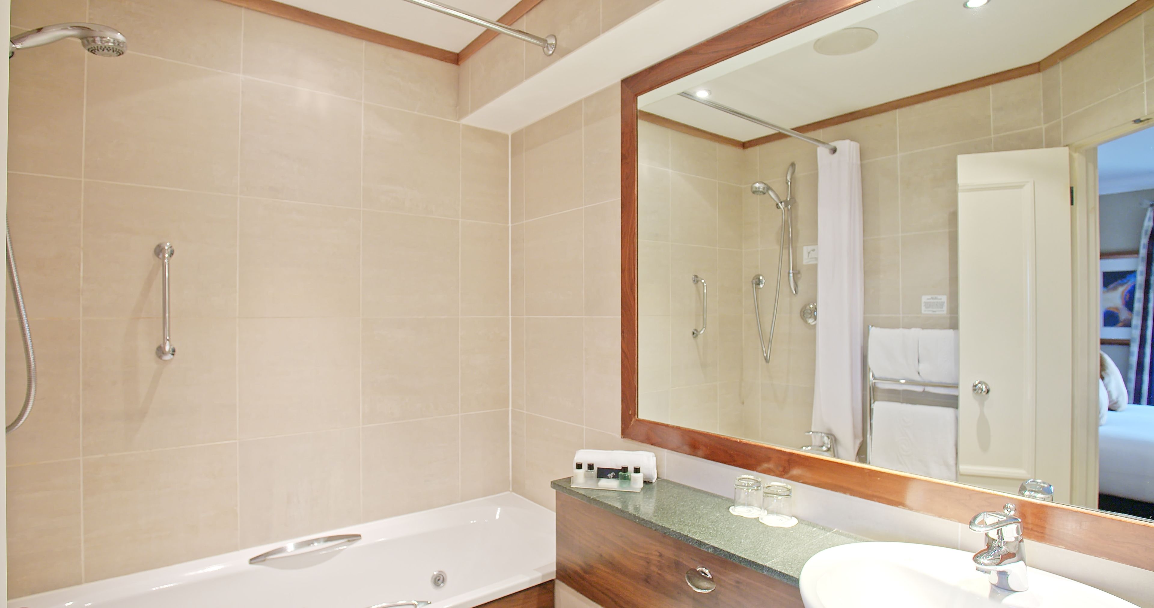 Un baño moderno con bañera, lavabo y un espejo grande.