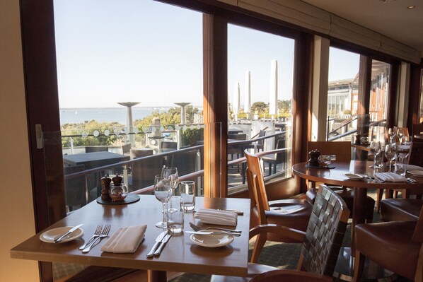 Un espace repas avec des tables préparées pour deux personnes, offrant une vue panoramique.