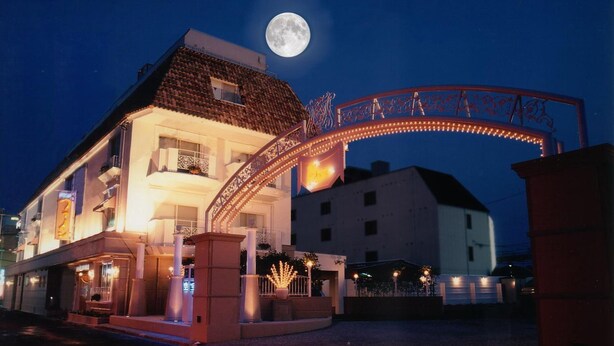 A hotel with a balcony, a moon in the sky, and a decorative archway.