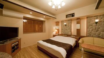 A hotel room with a bed, a TV, a stone wall, and a stone fireplace.