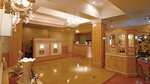 A spacious lobby with a marble floor, a reception desk, and a large, ornate cabinet.