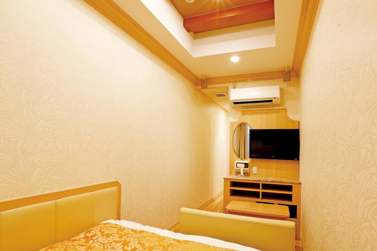 A hotel room with a bed, a TV, and a small desk with a mirror.