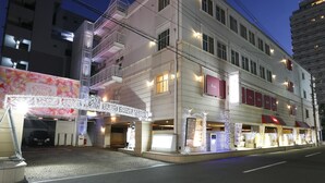 A multi-story building with a ground-level entrance, a covered area with a decorative arch, and multiple illuminated windows.
