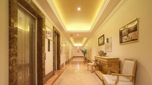 A hotel hallway with elevators, a reception desk, and a chair. - Hotel Fine Garden Kyoto Minami (Kyoto)