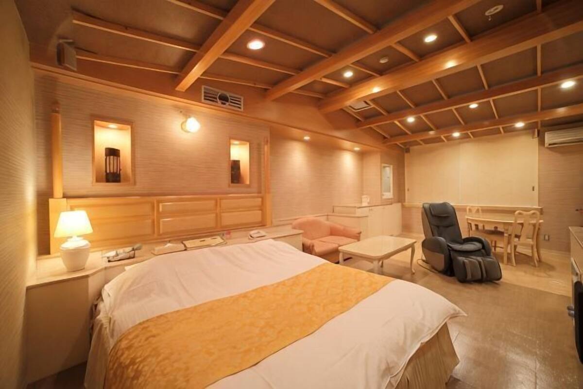 Una habitación de hotel con una cama grande, un escritorio, una silla y un sillón de masaje.