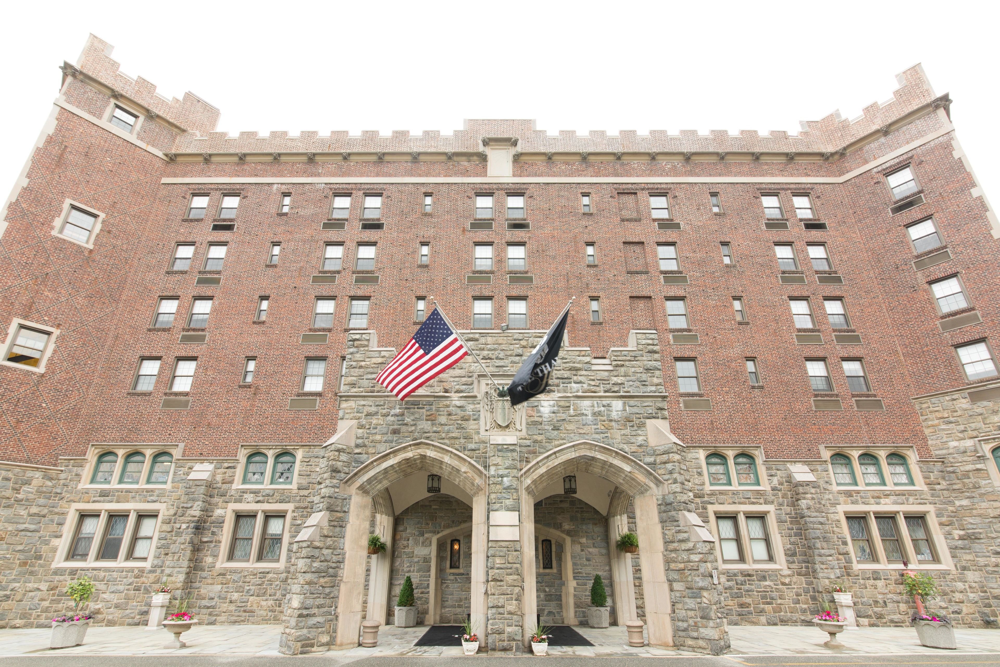 A large brick building with a symmetrical facade, multiple windows, and two prominent arches at the entrance.