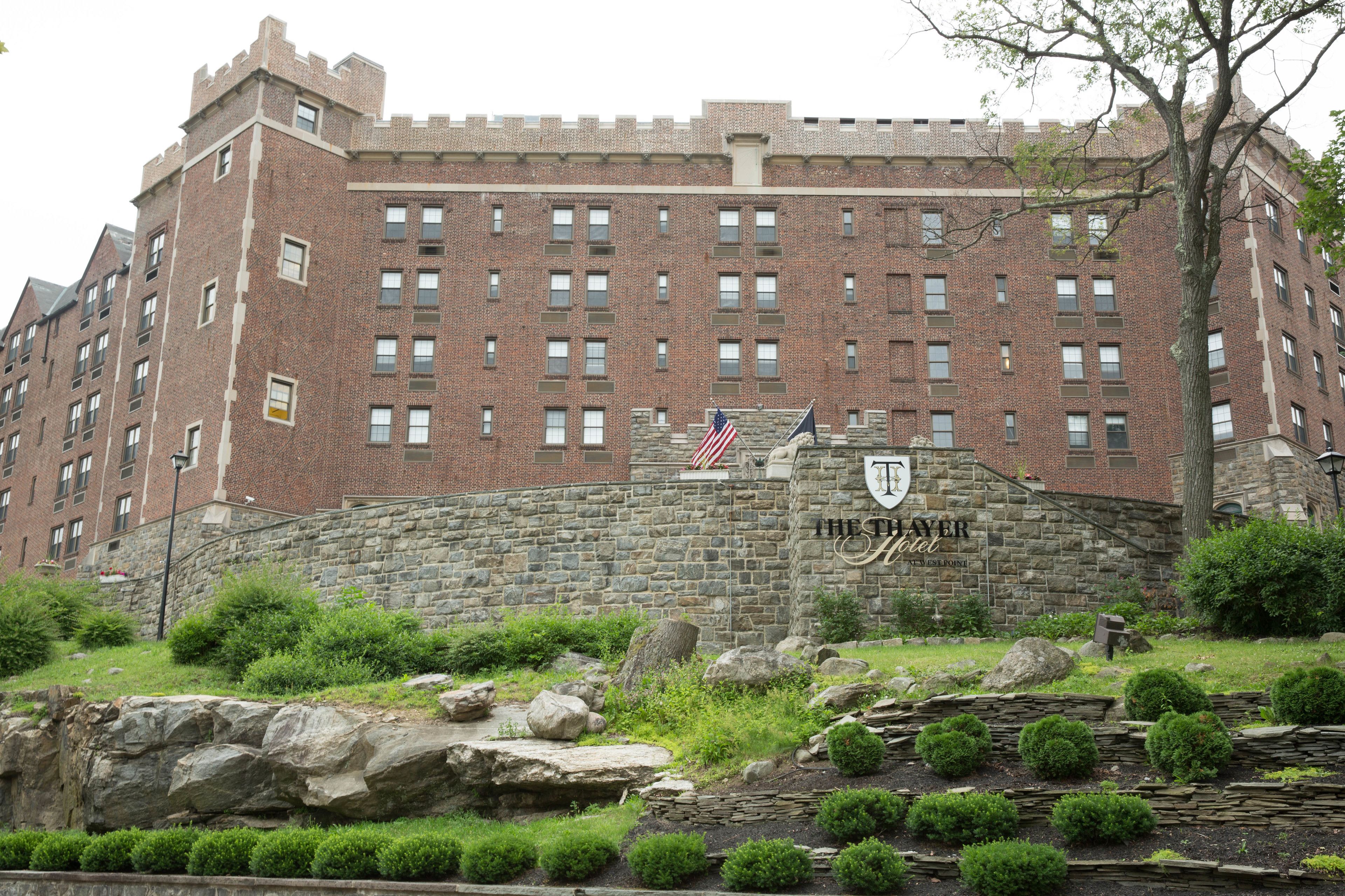 A large brick building with a stone wall and a sign that reads "Theater Hotel."
