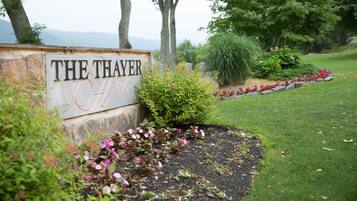 Letrero de 'The Thayer Hotel' con un jardín ajardinado al frente.