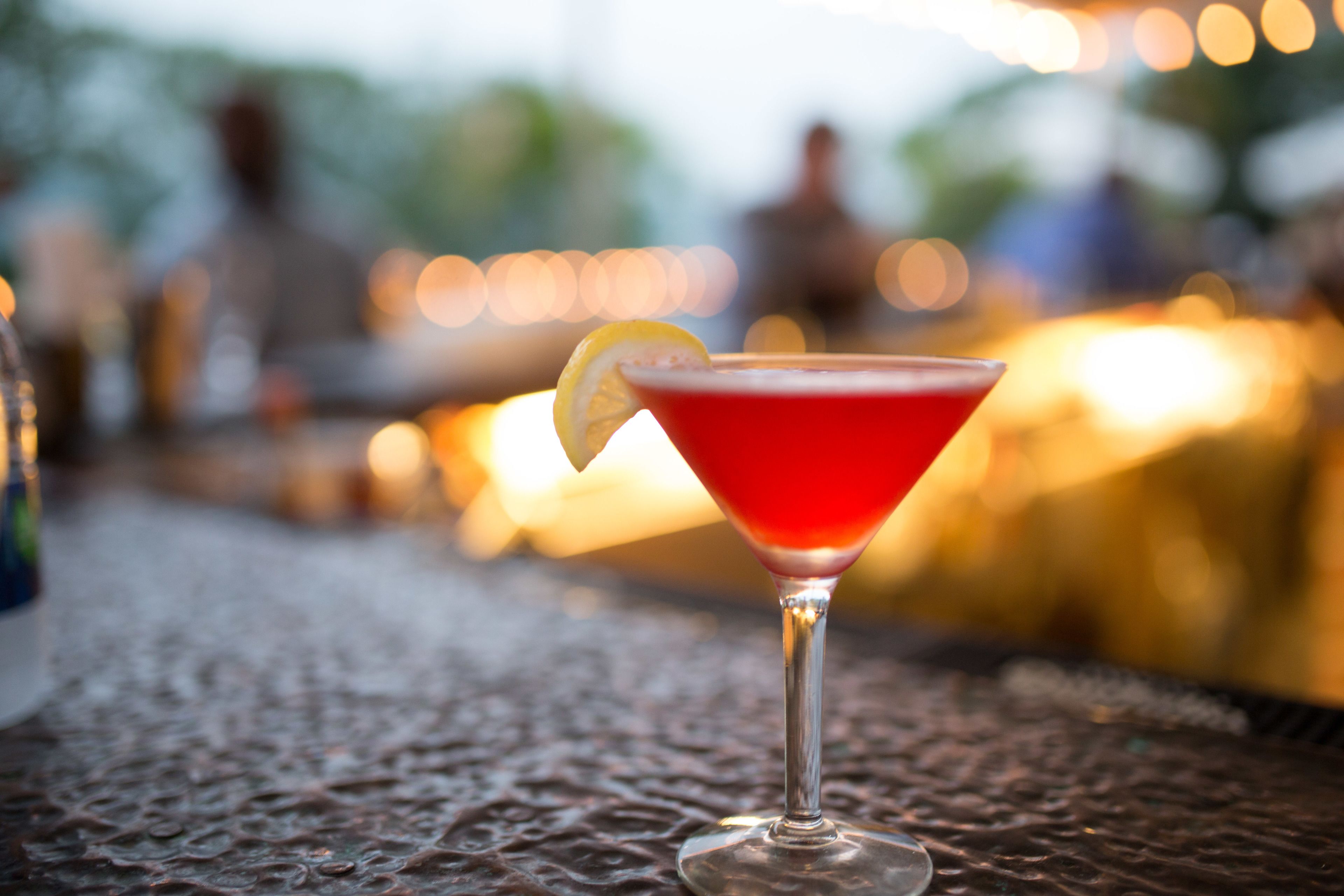 A martini glass with a lemon slice on a textured surface.