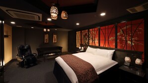 Ein Hotelzimmer mit einem großen Bett, einem Massagesessel, einem Schreibtisch und einer Wand mit einem roten abstrakten Design.