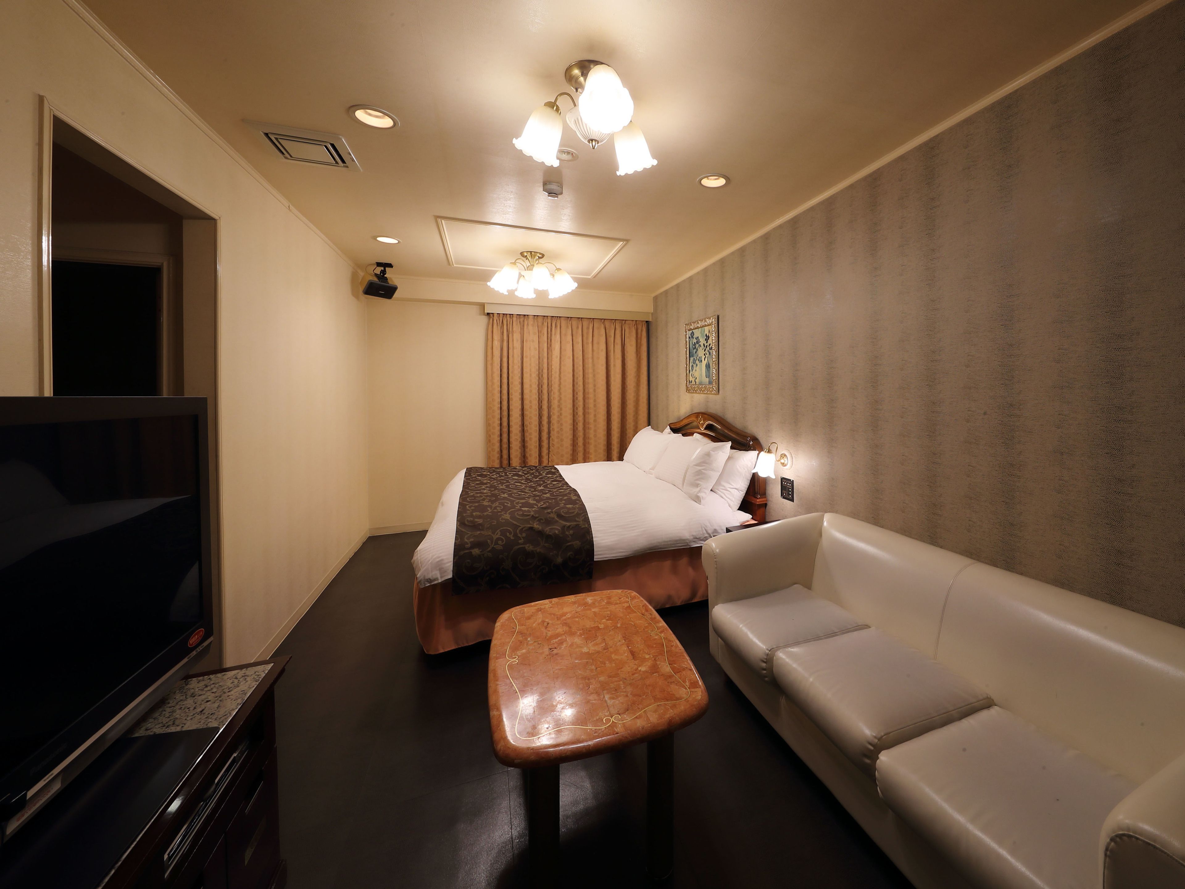 Une chambre d’hôtel avec un lit, une télévision, un canapé et une petite table.