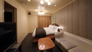 Une chambre d’hôtel avec un lit, une télévision, un canapé et une petite table.