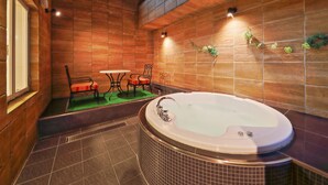 Ein modernes Badezimmer mit einer großen Badewanne, Holzwänden und einer kleinen Sitzecke mit Tisch und Stühlen.