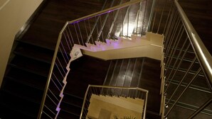 A spiral staircase with metal railings and a purple light strip.
