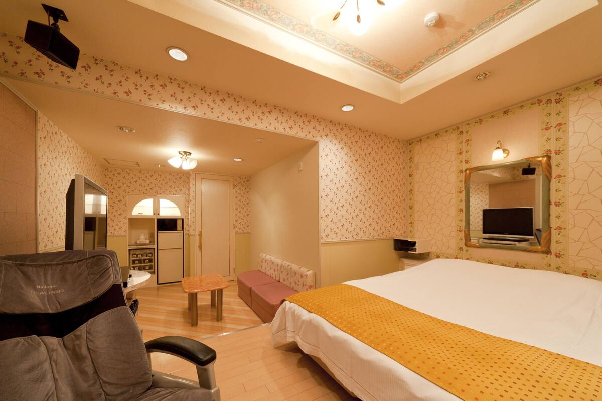 Ein Hotelzimmer mit einem großen Bett, einem Schreibtisch, einem Stuhl, einem Kleiderschrank und einem Fernseher.