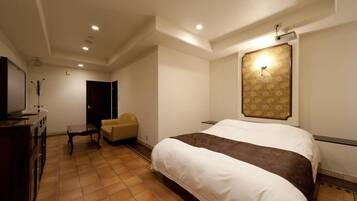 A hotel room with a large bed, a TV, a desk, and a chair.